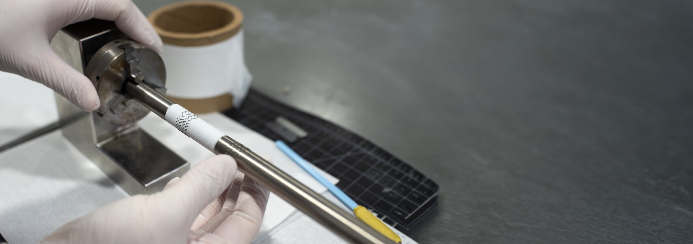 Medical device engineering — hands in gloves assembling a catheter component